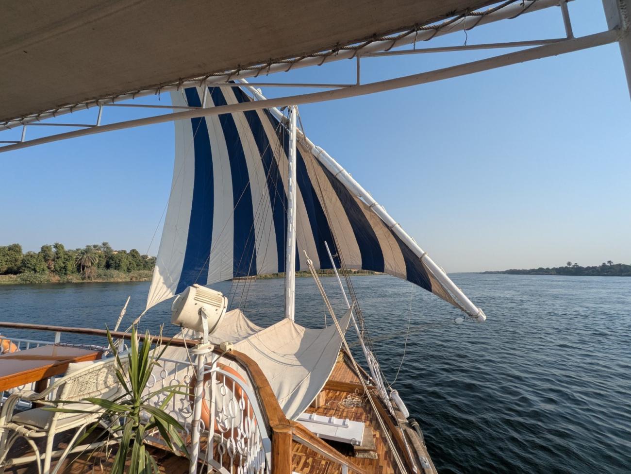 Foredeck of a boat with sail and view of the river Nile